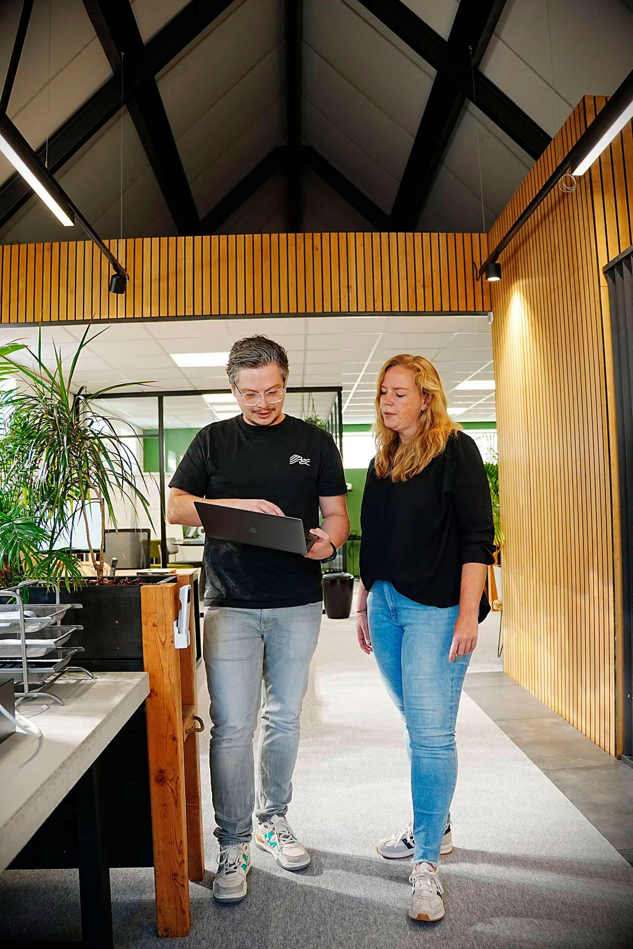 2 collega's staan in overleg met een laptop.