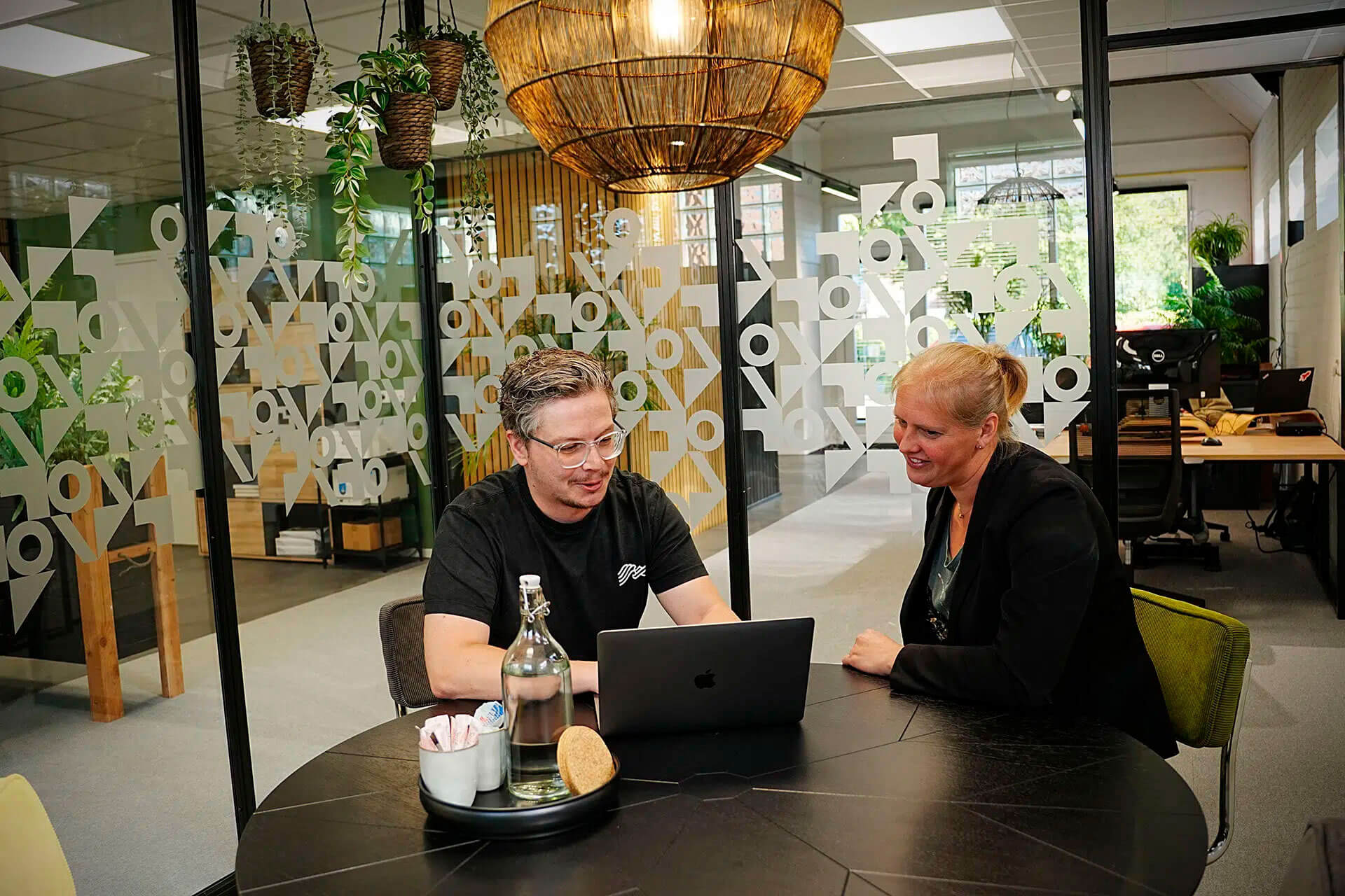 2 collega's in overleg achter een laptop.