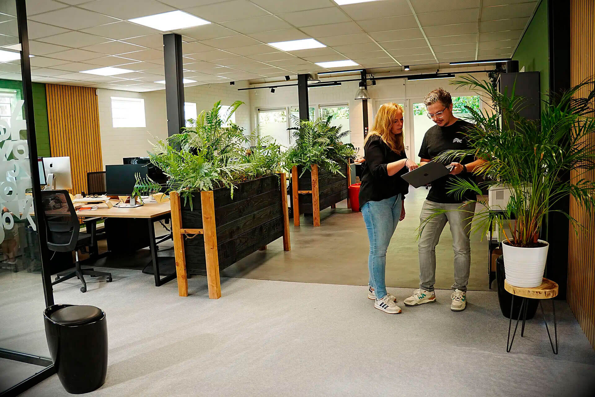 2 collega's staan in overleg met een laptop.