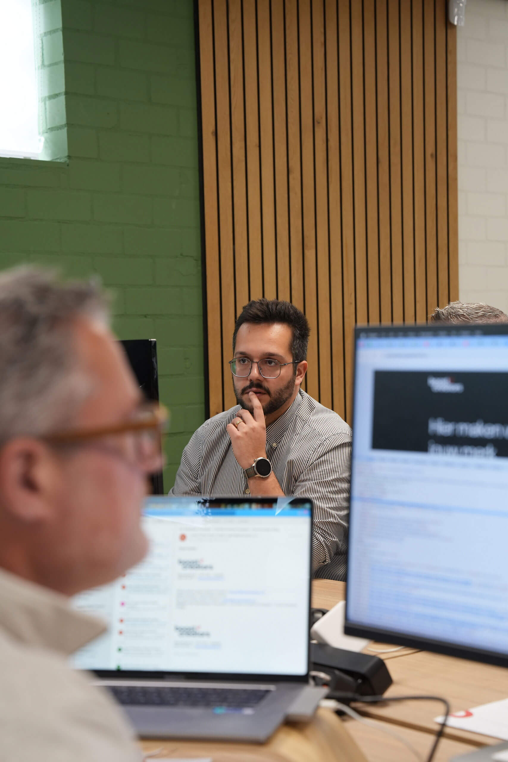Teamoverleg op kantoor waarbij een medewerker aandachtig luistert tijdens een bespreking.